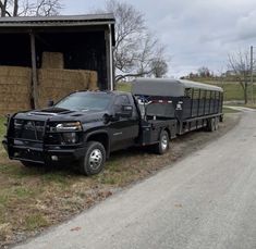 a black truck parked next to a barn