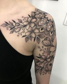 a woman's shoulder with flowers and leaves on it