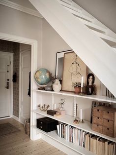 a bookshelf filled with lots of books next to a white door and stairs