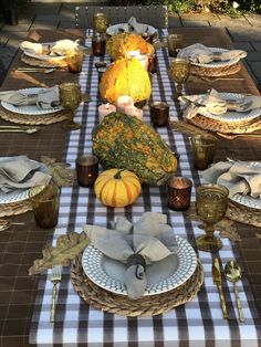 a table set for thanksgiving dinner with pumpkins, gourds and other decorations