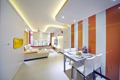 an open living room and dining area with white chairs, yellow walls and orange accents