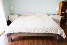 a bed with white sheets and pillows in a bedroom