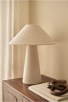 a lamp sitting on top of a wooden table next to a book and a bagel