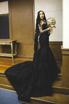 a mannequin wearing a black dress and holding flowers in front of a mirror