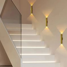 three lights are on the wall next to some white steps and stairs in a room