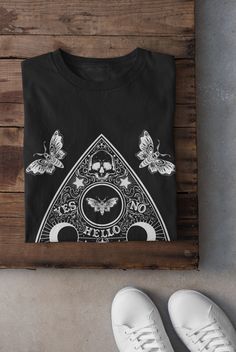 Thanks for stopping by! Ouija Board and Moths T-shirt Printed on a super soft, cotton tee Dispatched in 5 working days or sooner Unisex Free UK delivery Material: 100% ringspun cotton. Chest (to fit): S  34/36   M  38   L  40/42   XL  44/46   XXL  48/50 ECO-FRIENDLY Each garment is made to order, reducing extra material and energy that would be otherwise wasted We use DTG printing process which is easier on the environment than screen-printing Our ink is bright and also eco-friendly. Do not tumb Black Y2k Crew Neck Shirt, Black Y2k Shirt With Crew Neck, Black Y2k Style Crew Neck Shirt, Black Y2k T-shirt For Halloween, Black Y2k Style T-shirt For Halloween, Gothic Cotton Tops With Screen Print, Gothic Cotton Top With Screen Print, Gothic Printed Cotton Top, Y2k Black Shirt With Screen Print