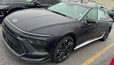 a black car parked in a parking lot next to other cars