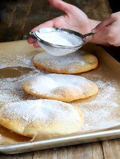 powdered sugar is being poured on top of three cookies that have been placed on a baking sheet