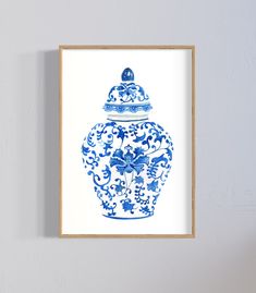 a blue and white vase is hanging on the wall next to a framed print that says,