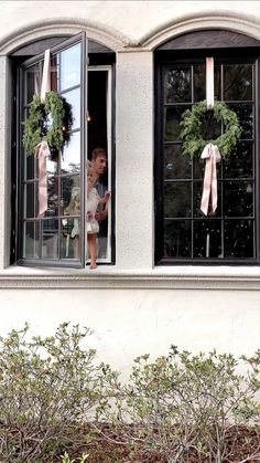 two children looking out the window with wreaths on them