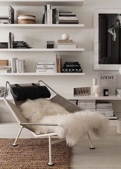 a white living room with bookshelves and a fur rug on the floor in front of it