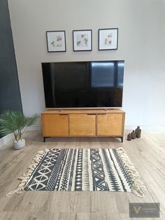 a flat screen tv sitting on top of a wooden entertainment center next to a potted plant