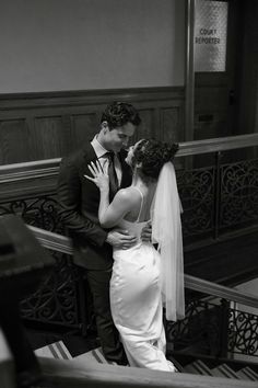 a bride and groom kissing on the stairs at their wedding reception in black and white