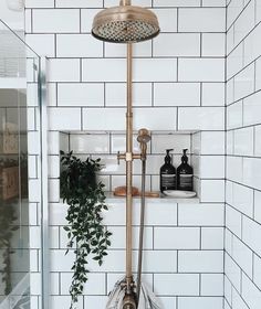 the shower head is mounted to the wall in this bathroom with white tiles and gold fixtures