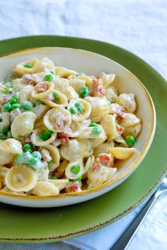 a bowl filled with pasta and peas on top of a green plate