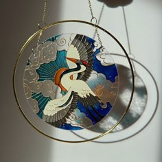 a bird is hanging from a chain on a glass plate with clouds in the background