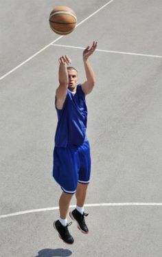 a young man is playing basketball on the court with his hands up in the air