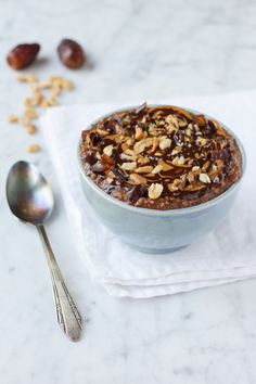 a blue bowl filled with granola and nuts on top of a white napkin next to a spoon