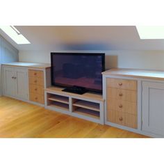 a flat screen tv sitting on top of a wooden cabinet in a room with white walls