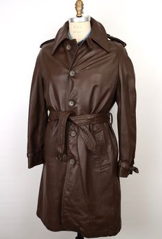 "\"The Leader of the Pack\" vintage 1970s leather trench coat in rich dark chocolate brown leather with matching marbled brown buttons, featuring: belted front with belt loops on sides/back and dark metal buckle; wide, deeply notched \"Ulster-style\" collar, which can lay flat or be popped up; 5-button front with top collar button and buttonhole loop for closing all the way up; angled front/hip pockets with cuffs; center vented back; and stylish knee length--A true vintage statement piece--Beaut Belted Brown Outerwear For Business, Classic Leather Outerwear With Belt Loops, Formal Leather Outerwear With Belt Loops, Formal Leather Belted Outerwear, Vintage Leather Outerwear For Business, Vintage Leather Business Outerwear, Vintage Belted Outerwear For Formal Occasions, Belted Vintage Outerwear For Formal Occasions, Leather Trench Coat Mens