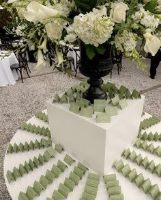 a vase filled with white flowers sitting on top of a table covered in green squares