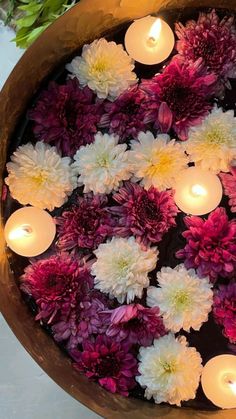 flowers and candles floating in water on a table