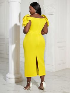 a woman in a yellow dress standing next to a pillar with her hands on her hips