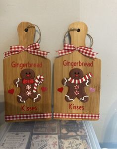 two gingerbread cookies on wooden cutting boards with gingherboard tags attached to them