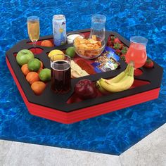 a tray with drinks, fruit and snacks on it next to a swimming pool area