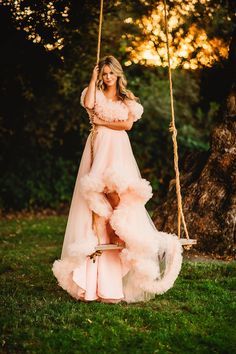 a woman in a pink dress on a swing