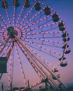 a ferris wheel is lit up at night with colorful lights on it's sides