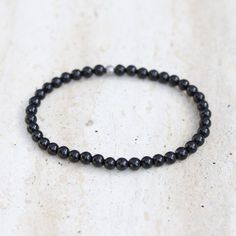 Shungite Delicate Bracelet Add a powerfully protective and comfortable Shungite bracelet to your stack! Made with genuine Shungite. Delicate & lightweight, perfect for everyday wear! Strung on our exclusive, thick, hitec elastic. Available in 3 sizes! Made in the USA. Ships in 1 Business Day! Shungite is also called "Miracle Stone" or "Stone of Life" as it is a very powerful stone known to protect the wearer, and it is very grounding. Bead size: 4mm SMALL: 6.5 inches/ 16.5 cm MEDIUM: 7.25 inches Shungite Bracelet, Delicate Bracelet, Large Black, 20 Cm, Everyday Wear, Ships, Elastic, Bracelet, Beads