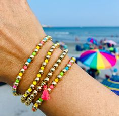 a close up of a person's arm with bracelets on it at the beach