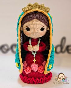 a crocheted doll is dressed in a red dress with a gold tiara