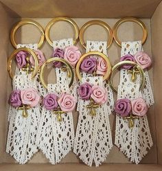 six pink roses and gold rings are in a box with white lace on the bottom