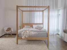 a bedroom with a four poster bed and white curtains