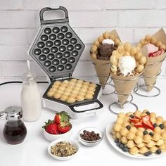 an assortment of desserts and pastries are arranged on a white table with a brick wall in the background