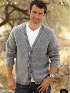 a man standing in front of a tree wearing a cardigan sweater and blue jeans