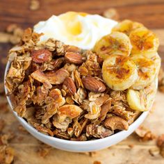 a bowl filled with granola, bananas and yogurt on top of a wooden table