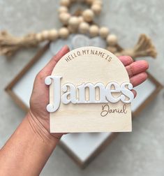 a person holding up a wooden name tag that says, hello my name is james daniel