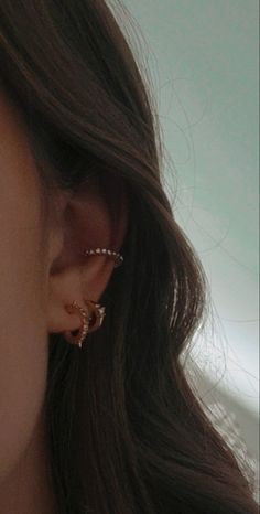 a close up of a person's ear and nose wearing gold earrings with pearls