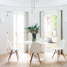 a white dining room table with chairs and a laptop