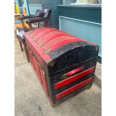 an old trunk sitting on the sidewalk next to a chair