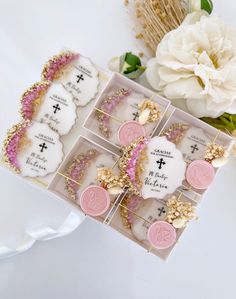 a box filled with lots of pink and white cookies on top of a table next to flowers