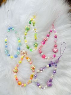 three necklaces are laying on top of a white fur covered surface with beads and charms