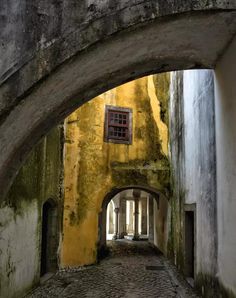 an old alley way with yellow walls and cobblestone flooring in the middle