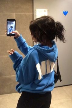 a woman taking a selfie in front of a bathroom mirror with her cell phone