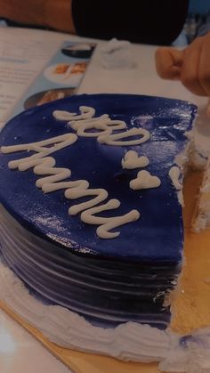 a blue cake with white frosting that says happy new year on it and is being cut