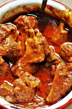 a bowl filled with meat and sauce on top of a table