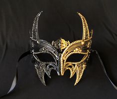 This luxury Venetian masquerade mask is made of a lightweight metal and accented with beaded trim. Mask also is hand painted half black and gold.  Black silk ribbon ties attached.  Size 7" x 7". Stand out at you next masquerade mask party with this stunning mask! Gothic Gold Masks And Prosthetics For Costume, Gold Venetian Mask For Halloween, Gothic Masks For Mardi Gras Theater, Gothic Masks For Theater And Mardi Gras, Black Venetian Masquerade Mask For Carnival, Gothic Gold Masquerade Mask For Carnival, Gold Gothic Masquerade Mask For Carnival, Gold Costume Masks For Halloween, Gold Gothic Mask